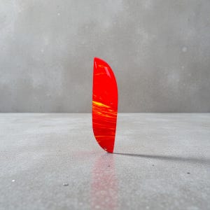 以下が含まれることがあります： 鮮やかな赤と黄色の抽象的なアクリルペンダント。ペンダントは湾曲した細長い形状で、下部に小さな穴があります。デザインは赤の中に黄色の縞模様があり、ダイナミックな視覚効果を生み出しています。長さ約6cm。