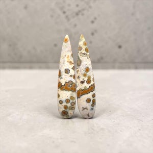 May include: A set of three ceramic mugs with a speckled, matte finish. The mugs are in shades of cream, light gray, and dark gray. Each mug has a simple, minimalist design, perfect for coffee or tea.