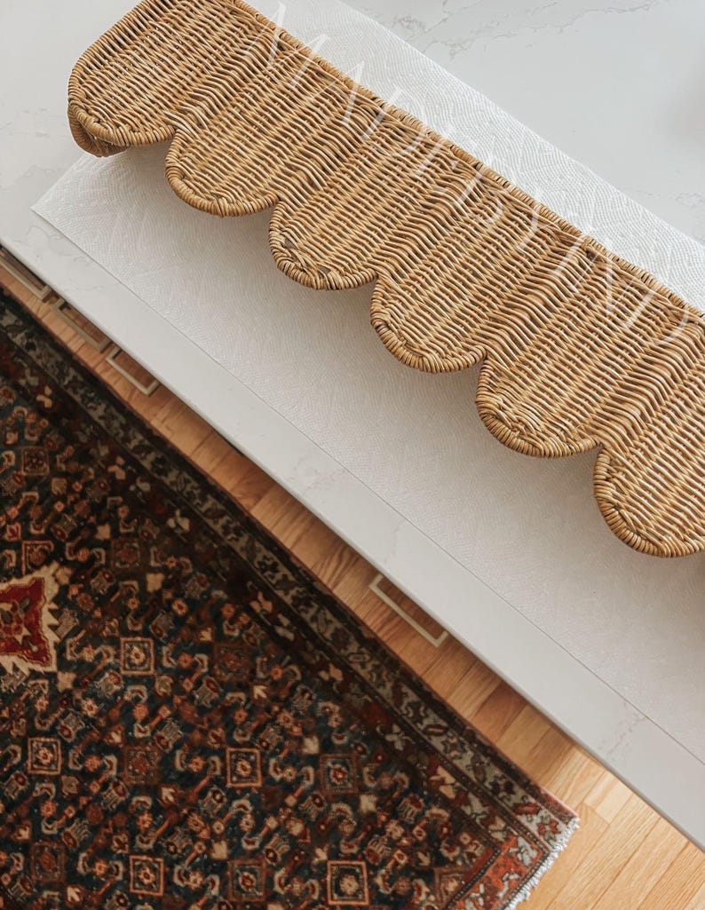 Puede incluir: Un cenefa rectangular de mimbre tejido con un borde inferior festoneado. El material natural de color marr&oacute;n claro est&aacute; estrechamente entrelazado en un patr&oacute;n repetitivo, creando una pieza decorativa texturizada con un dise&ntilde;o ondulado.