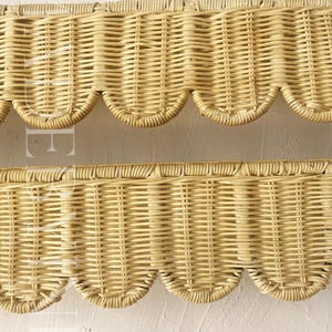 Puede incluir: Dos tiras horizontales de material de mimbre tejido de color tostado claro con un dise&ntilde;o de borde festoneado repetitivo a lo largo de la parte inferior. La textura de la fibra natural es visible en todo el tejido, creando un patr&oacute;n uniforme.