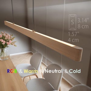 Op de afbeelding: Een houten lamp met warm wit licht. De lamp is 8 cm breed en 4 cm hoog. Hij hangt boven een tafel met twee stoelen. De lamp heeft RGB-, warm-, neutraal- en koudlichtinstellingen.