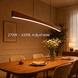 May include: A long, curved wooden pendant light fixture suspended from the ceiling, featuring a continuous integrated LED light strip. The text 2700K – 6500K Adjustable is visible on the image, indicating the colour temperature range of the light.
