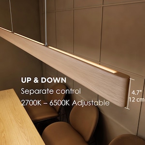 May include: A wooden, rectangular pendant light fixture with a built-in light strip. The fixture is suspended from the ceiling and has the text "UP & DOWN Separate control 2700K - 6500K Adjustable". The light is 4.7 inches (12 cm) wide.