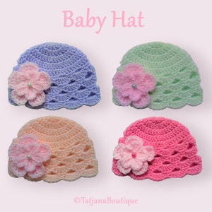 May include: Four crocheted baby hats in different colors: light blue, light green, peach, and pink. Each hat has a crocheted flower with a pearl in the center.