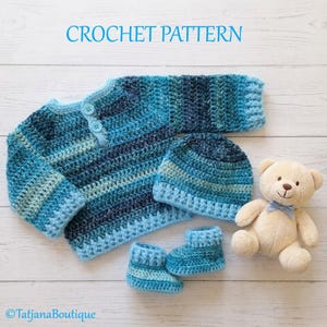 Op de afbeelding: Een baby haakset in blauwe tinten, bestaande uit een trui, muts en babyschoentjes. De trui heeft knopen en de muts past erbij. Een teddybeer staat naast de set. De tekst "CROCHET PATTERN" staat bovenaan.