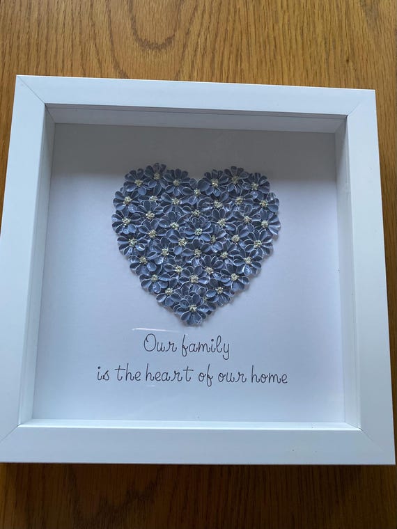 A grey/ blue heart made with handmade flowers and the quote Our family is the heart of our home, printed underneath and then framed.