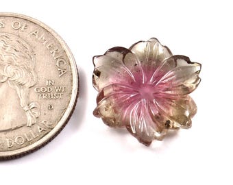May include: A carved gemstone in the shape of a flower, with a quarter coin for size comparison. The flower has a pink center that fades to clear and brown petals. The gemstone is on a white background.