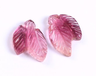 May include: Two pink carved gemstone leaves. The leaves are translucent and have a striated pattern.