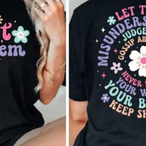 May include: Two black t-shirts with colorful floral designs and text. The front shirt says "Let them" and the back shirt says "Let them misunderstand you, judge you, gossip about you. Never doubt your worth! Your beauty! Keep shining!"