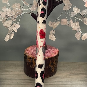 May include: A black and white leopard print pen with a pink and red heart design and the word "Love" on it. The pen is sitting on a pink and brown rock.