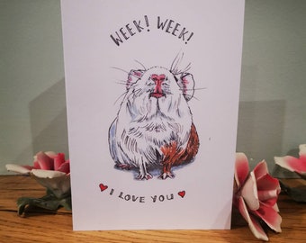 May include: A white and brown guinea pig with a pink nose and red eyes is looking up. The card says "Week! Week! I love you" with two red hearts.