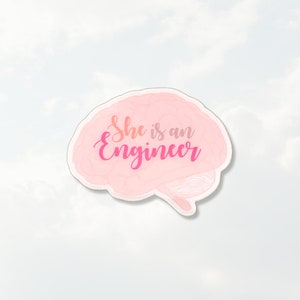 May include: A die-cut sticker shaped like a human brain in a light pink color. The text "She is an Engineer" is printed across the center of the brain in a cursive, dark pink font. The sticker has a thin white border around the entire edge.