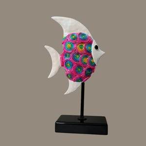 Puede incluir: Escultura decorativa de pez con cabeza, aletas y cola blancas. El cuerpo es rosa con diseños de espirales coloridas. La escultura está montada sobre un soporte negro.