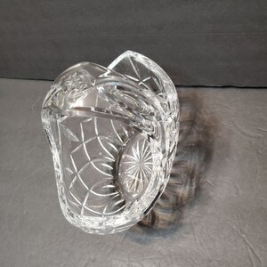 Pu&ograve; includere: Un cestino di cristallo trasparente tagliato con un design curvo unico. Il cestino presenta un motivo a diamante e dettagli a stella sulla base. Il bordo ha un bordo smerlato decorativo. Il cristallo riflette la luce.