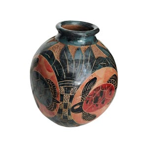 Może przedstawiać: Okrągły, ręcznie robiony ceramiczny wazon z ciemnozieloną obwódką i czarnym korpusem. Wazon posiada wzór żółwi w kolorze czerwonym i czarnym, z geometrycznym wzorem. Wazon jest przedmiotem dekoracyjnym.