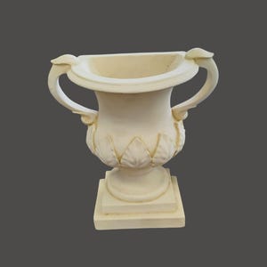 May include: Off-white, classical-style urn with two curved handles and a decorative leaf pattern. The urn sits on a square base, and the overall design is symmetrical. The vessel is made of a solid material, possibly stone or plaster.
