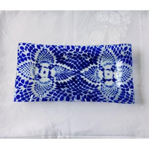 Può includere: Piatto rettangolare in vetro con un motivo blu e bianco a forma di pizzo. Il piatto ha un bordo leggermente ondulato ed è posto su uno sfondo bianco. Il design blu è intricato e simmetrico, simile a un centrino.