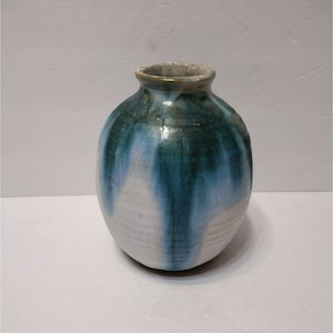 May include: A handmade ceramic vase with a rounded body and a narrow neck. The vase features a color palette of white, blue, and green, with the colors blending and dripping down the sides. The vase is a decorative item.
