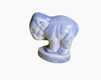 Può includere: Piccola statuina di elefante in ceramica blu chiaro. L'elefante è in piedi su una piccola base, con la proboscide rivolta verso il basso e le orecchie visibili. Fatto in Inghilterra.