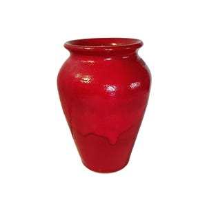 May include: A vibrant red ceramic vase with a glossy finish. The vase has a rounded body and a slightly flared rim. The red glaze has subtle variations in tone, adding depth to the design. This decorative vase is suitable for home decor.