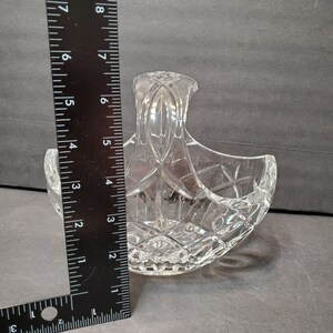 Pu&ograve; includere: Un cestino di cristallo trasparente con manico, con un motivo a diamante. Il cestino &egrave; alto circa 15 cm, misurato con un righello nero. Il cestino &egrave; progettato con una forma curva e un manico decorativo.