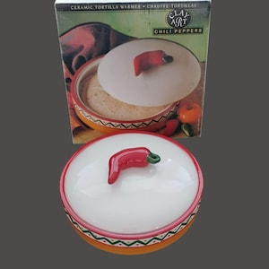 May include: Ceramic tortilla warmer with a white lid featuring a red chili pepper handle. The warmer has a red, green, and orange design around the base. The box behind it reads "Ceramic Tortilla Warmer" and "Chili Peppers".