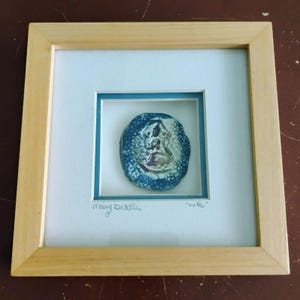 Könnte beinhalten: Gerahmtes Kunstwerk mit einem abstrakten blauen und weißen Design. Das Kunstwerk ist in einem weißen Passepartout und einem hellen Holzrahmen eingefasst. Die Signatur des Künstlers, "Mary Diddle", und das Wort "wife" sind handschriftlich.