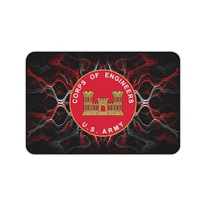 May include: Rectangular mousepad featuring the U.S. Army Corps of Engineers emblem. The emblem is a red circle with a gold castle design and the text "CORPS OF ENGINEERS" and "U.S. ARMY". The background has a black and red abstract design.