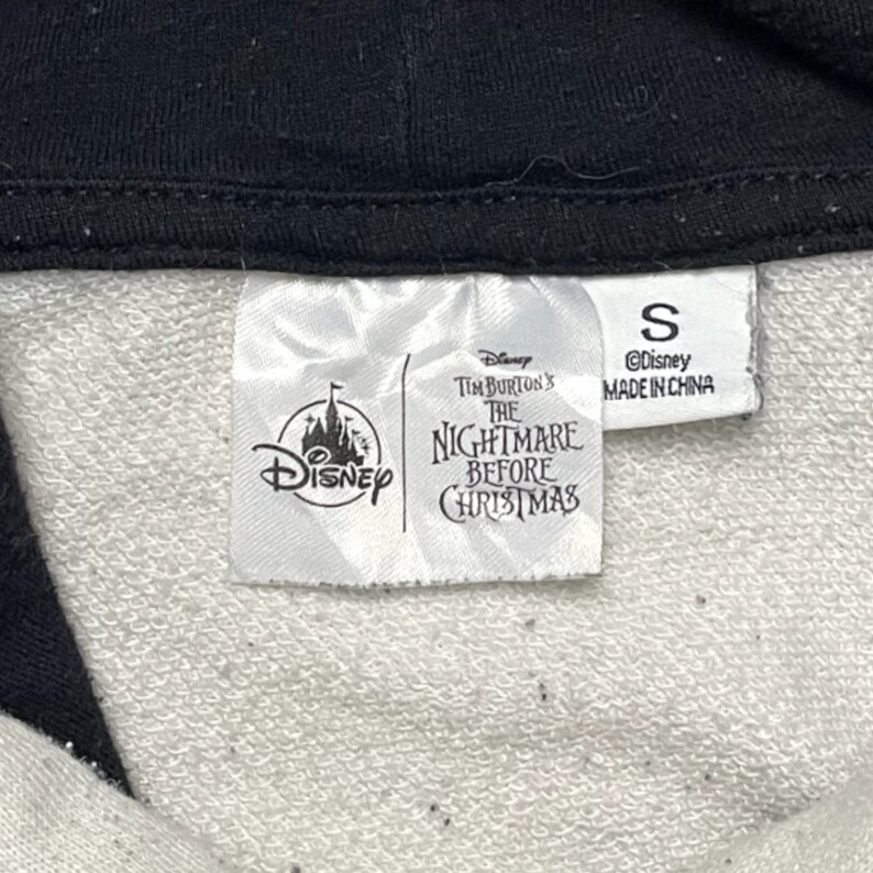 May include: White tag with black text that reads "Disney Tim Burton's The Nightmare Before Christmas" and a Disney logo. A smaller white tag with black text reads "S &copy;Disney Made in China".