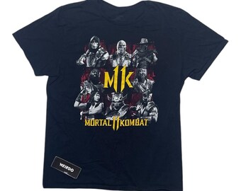 Könnte beinhalten: Ein marineblaues T-Shirt mit einem Grafikdruck von Charakteren aus dem Videospiel Mortal Kombat. Die Grafik zeigt die Charaktere in Kampfpose mit dem Mortal Kombat-Logo in Gelb. Der Text "MK" ist ebenfalls in Gelb.