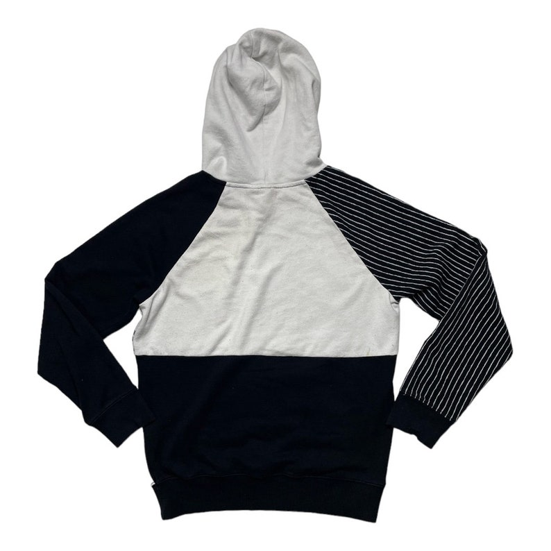 May include: A black and white striped hoodie with a white hood and a black and white striped sleeve. The hoodie has a black bottom and a white middle section.
