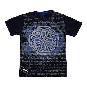 Może przedstawiać: Czarny T-shirt z niebieskim i srebrnym wzorem celtyckiego węzła. Koszulka ma postarzony wygląd i małą metkę "WEIRDO" w lewym dolnym rogu.