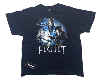 Könnte beinhalten: Schwarzes T-Shirt mit einem Grafikdruck von Sub-Zero aus Mortal Kombat. Die Grafik zeigt Sub-Zero in Kampfpose mit einem blau-weißen Kostüm. Der Text "FIGHT" ist unterhalb der Grafik aufgedruckt.