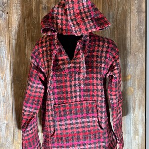 May include: A red, black, and pink plaid hooded sweatshirt with a drawstring hood and a kangaroo pocket.