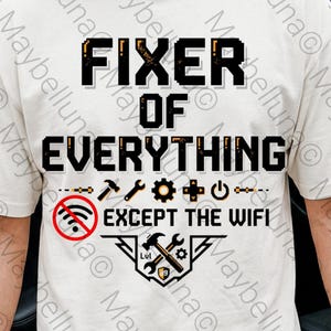 Könnte beinhalten: Cremefarbenes T-Shirt mit dem Text "FIXER OF EVERYTHING EXCEPT THE WIFI" in Schwarz und Orange. Das Design enthält Werkzeugsymbole und ein Kein-WLAN-Symbol. Das T-Shirt wird von einer Person getragen.