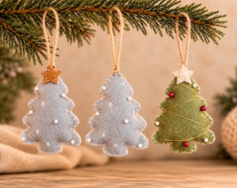 May include: Three felt Christmas tree ornaments hanging from a branch. Two are light blue with white embroidered stars and beads, topped with a brown star. The third is green with gold thread, red beads, and a white star topper.