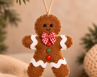 May include: A brown felt gingerbread man ornament featuring white rickrack trim on the arms and legs, a red and white checkered bow tie, and two small buttons in red and green. The figure has black bead eyes and a stitched smile.