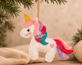 May include: A white felt unicorn ornament featuring a gold glitter horn, pink cheeks, and a multi-colored glitter mane and tail in shades of pink, purple, red, and teal. A small pink heart is stitched on the flank, and a jute twine loop is attached.