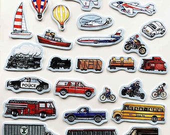 May include: A collection of colorful transportation-themed felt cutouts, including airplanes, trains, cars, boats, and hot air balloons. The vehicles are in various colors and styles, with some featuring text like "POLICE" and "School Bus."
