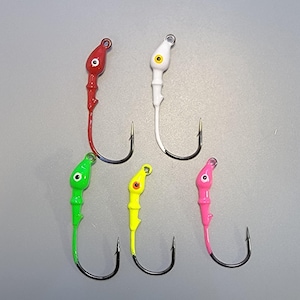May include: Six brightly colored fishing jigs. The jigs have a painted head with an eye and a curved hook. Colors include red, white, green, yellow, and pink. The hooks are black.