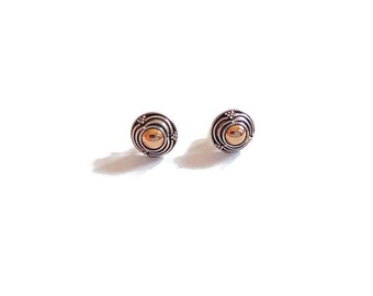 May include: A pair of round stud earrings featuring a polished gold-tone center sphere surrounded by concentric silver-tone rings with a textured, oxidized finish. The design includes small beaded accents along the outer edge of each circular earring.