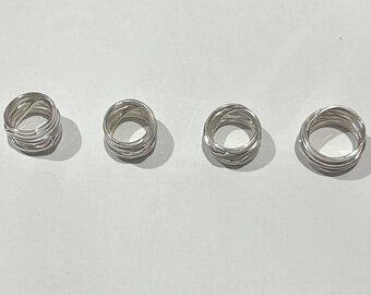 May include: Four silver-colored rings arranged in a horizontal row. Each ring is constructed from multiple strands of wire wrapped together to form a thick, circular band with a textured, layered appearance and a polished, reflective metallic finish.