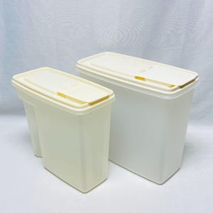 May include: Two rectangular off-white plastic storage containers with matching lids. Each container features a hinged flip-top opening on the lid. The containers are semi-translucent and have a smooth, vertical design for organized pantry storage.