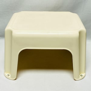 May include: A cream-colored, square plastic step stool. The stool has a textured top surface and rounded corners. The legs are curved, providing stability. The stool is designed for indoor or outdoor use.