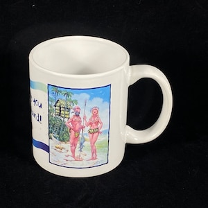 Könnte beinhalten: Weiße Keramiktasse mit einer farbenfrohen Illustration von zwei Cartoonfiguren an einem tropischen Strand. Die Tasse hat einen gebogenen Henkel und den Text "Thank you for being so kind!" auf der Seite.