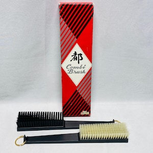 May include: A rectangular red and black box labeled Combi Brush with Japanese characters, accompanied by two black-handled brushes. One brush features stiff black bristles, while the other has light-colored bristles and a gold-toned metal ring.