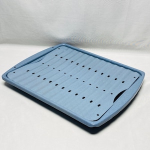 Puede incluir: Una bandeja de horno rectangular de color azul claro que incluye una rejilla interior extraíble con superficie ondulada y múltiples orificios de ventilación. La bandeja tiene un acabado moteado y asas integradas en los lados cortos.
