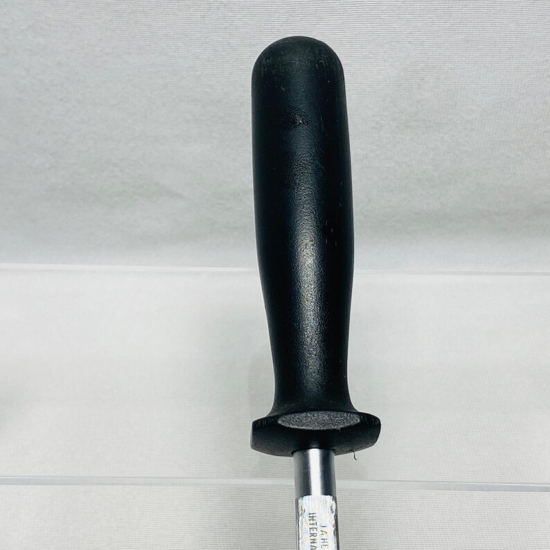 May include: A black handled steel knife sharpener. The handle is a solid black color and has a rounded top. The steel rod is silver and has text printed on it. The sharpener is designed for sharpening knives.