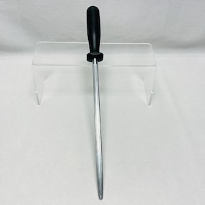 May include: A silver steel knife sharpening rod with a black handle. The rod is long and cylindrical, designed for honing the edge of knives. The handle is made of a smooth, solid material.