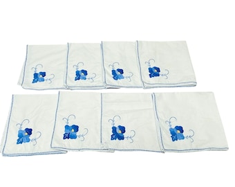 8 servilletas vintage de algodón blanco con bordado floral azul y bordes festoneados.